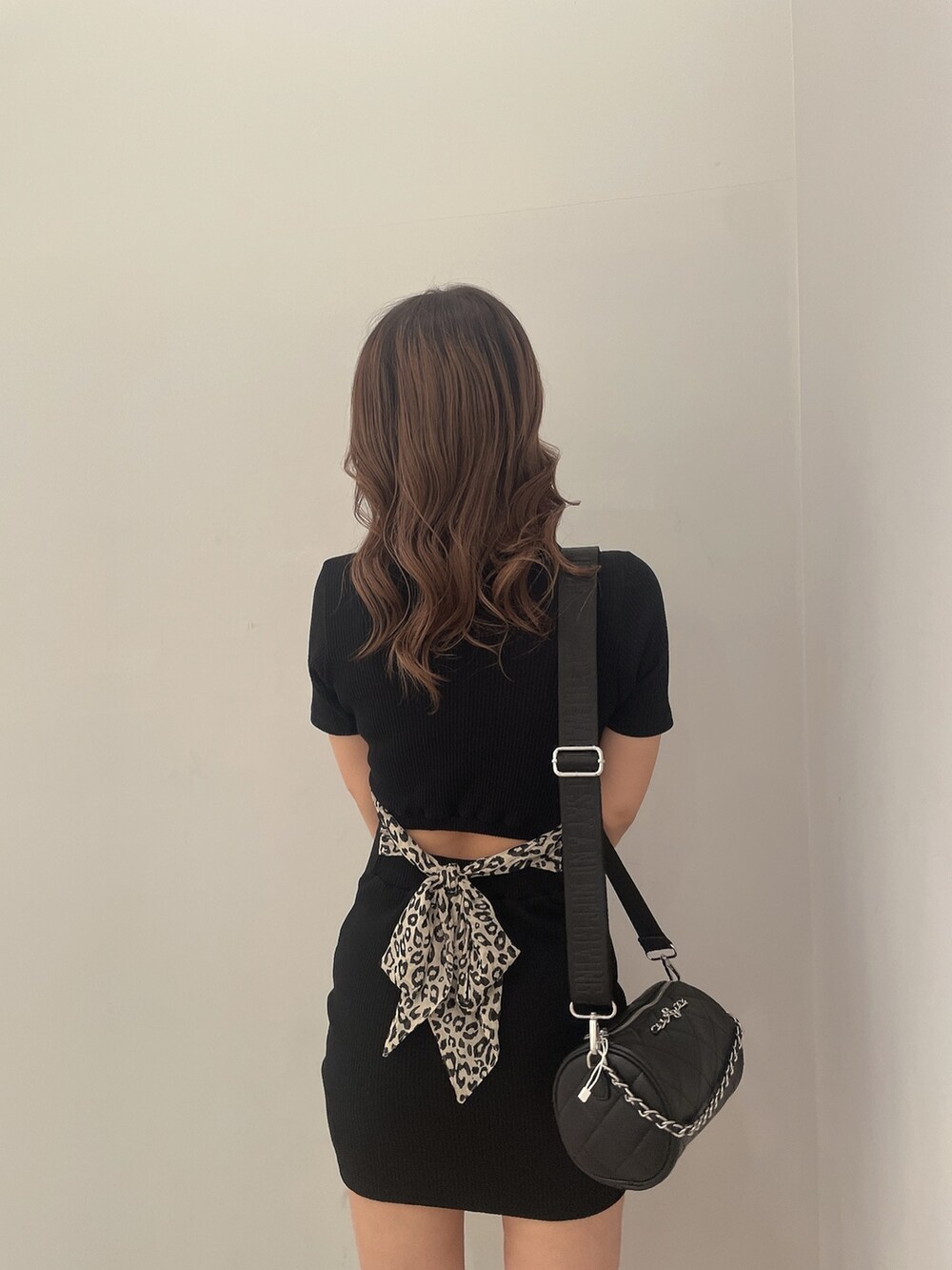 ブラック系のハンドバッグ、ブラック系のブーツ、ブラック系のワンピースを着用したレディースの冬コーディネートの6枚目の写真