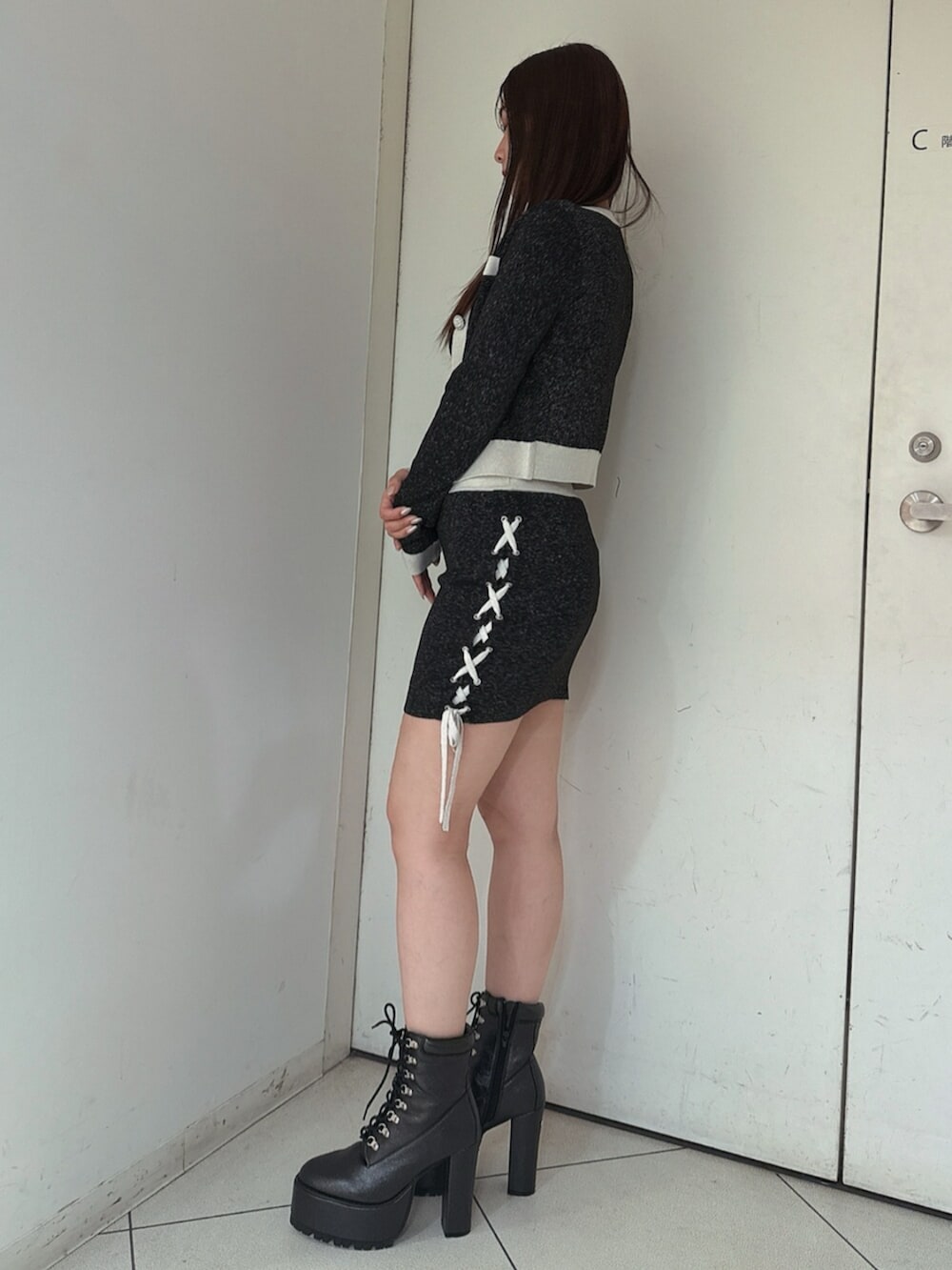 ブラック系のニット/セーター、ブラック系のスカート、ブラック系のブーツを着用したレディースの春コーディネートの2枚目の写真