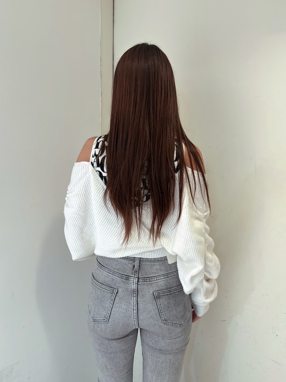 グレー系のデニムパンツ、ブラック系のブーツ、ホワイト系のニット/セーターを着用したレディースの秋コーディネートの6枚目の写真
