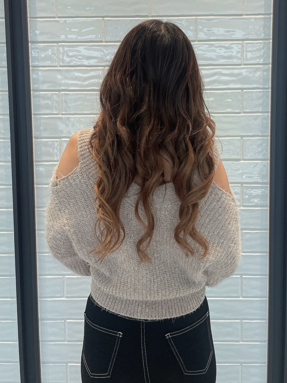 ベージュ系のニット/セーター、ブラック系のデニムパンツ、ブラック系のブーツを着用したレディースの秋コーディネートの6枚目の写真