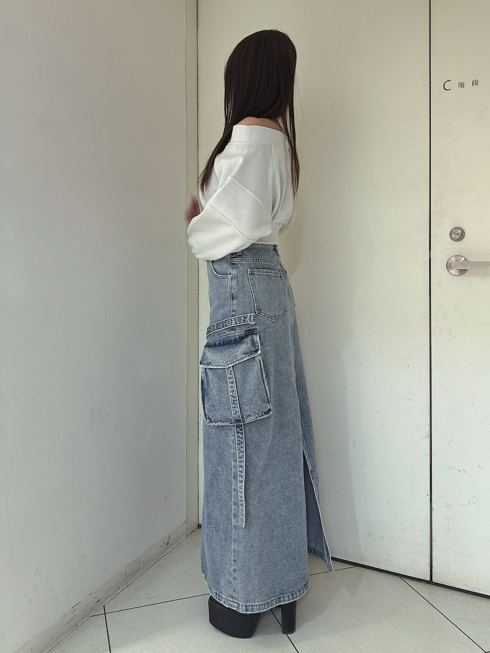 ブルー系のデニムスカート、ホワイト系のTシャツ/カットソー、ブラック系のブーツを着用したレディースの冬コーディネートの2枚目の写真