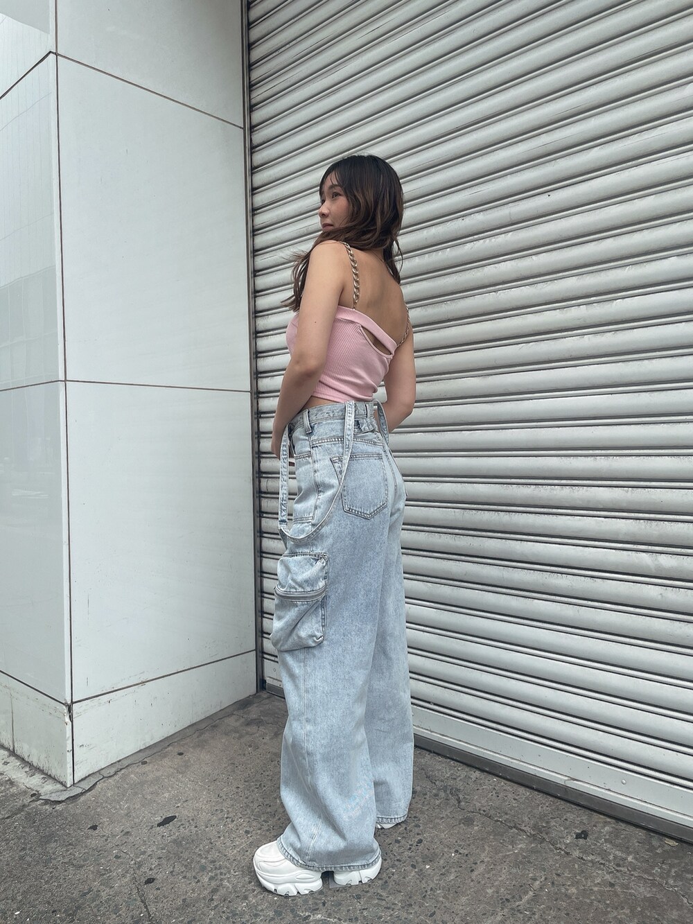 ピンク系のキャミソール、ブルー系のデニムパンツ、ホワイト系のスニーカーを着用したレディースの夏コーディネートの2枚目の写真