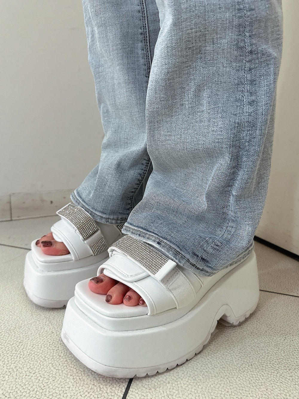 ブルー系のデニムパンツ、ホワイト系のチューブトップ、ホワイト系のシャツ/ブラウスを着用したレディースの春コーディネートの9枚目の写真