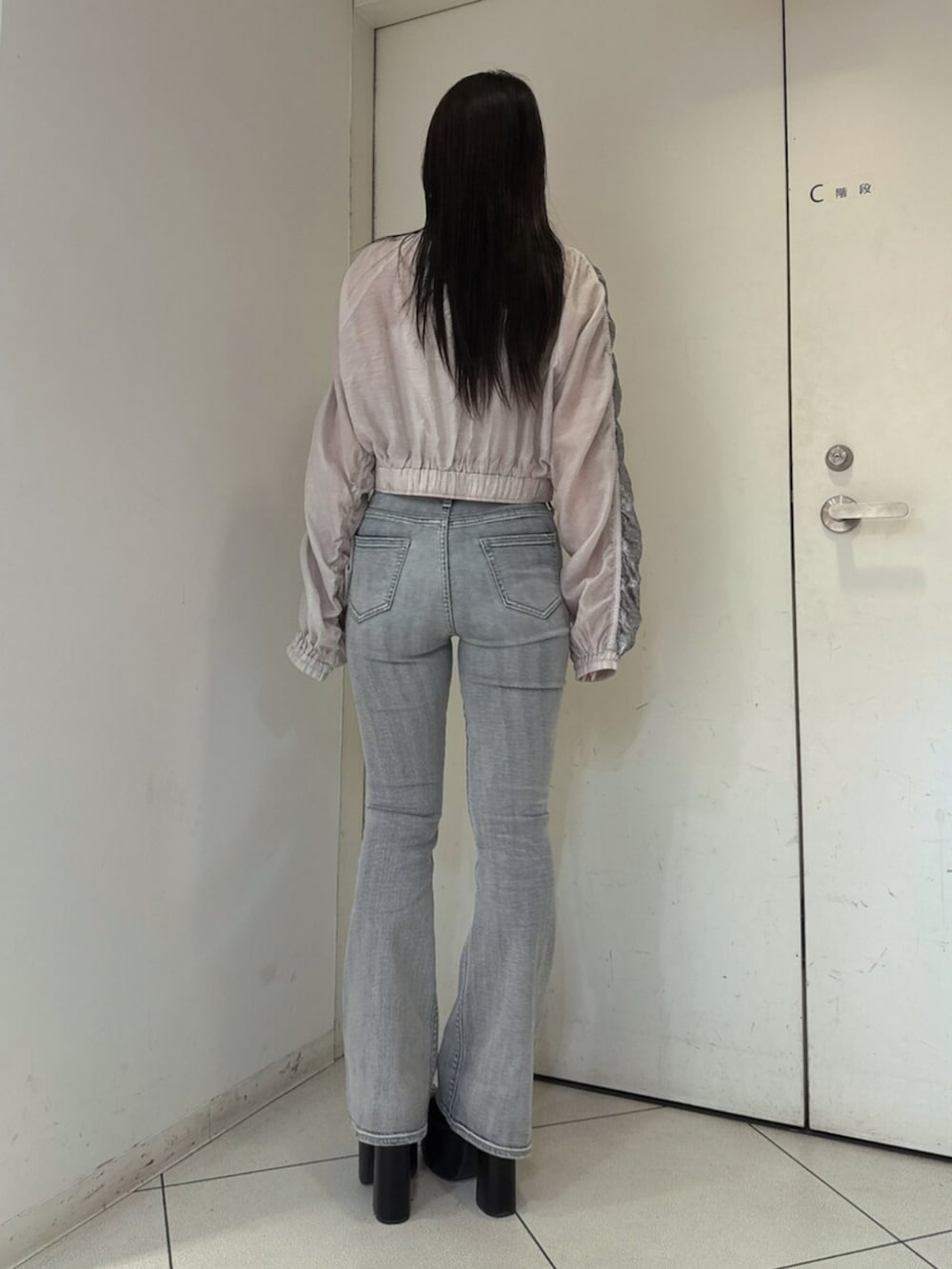 ブルー系のデニムパンツ、ブラック系のサンダル、ホワイト系のブルゾンを着用したレディースの春コーディネートの3枚目の写真
