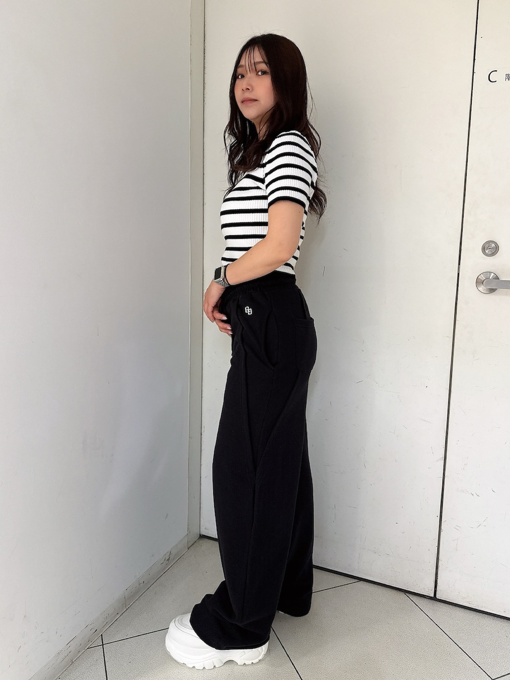 ブラック系のスウェットパンツ、ホワイト系のスニーカー、ブラック系のニット/セーターを着用したレディースの春コーディネートの2枚目の写真