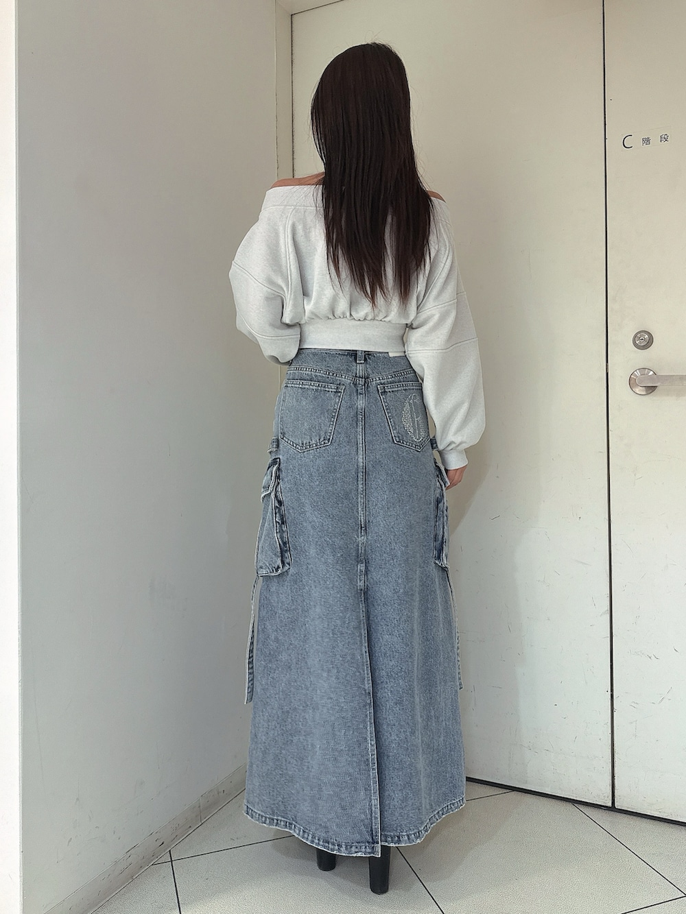 ブルー系のデニムスカート、ホワイト系のTシャツ/カットソー、ブラック系のブーツを着用したレディースの冬コーディネートの3枚目の写真