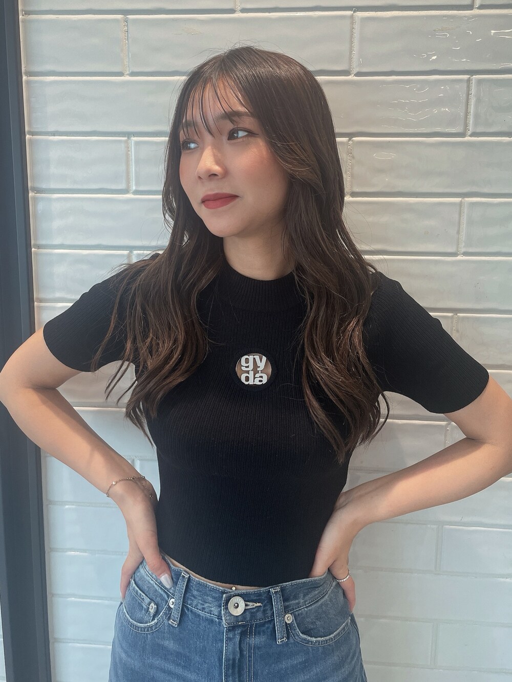 ブラック系のニット/セーター、ブラック系のサンダル、ブルー系のデニムパンツを着用したレディースの夏コーディネートの4枚目の写真