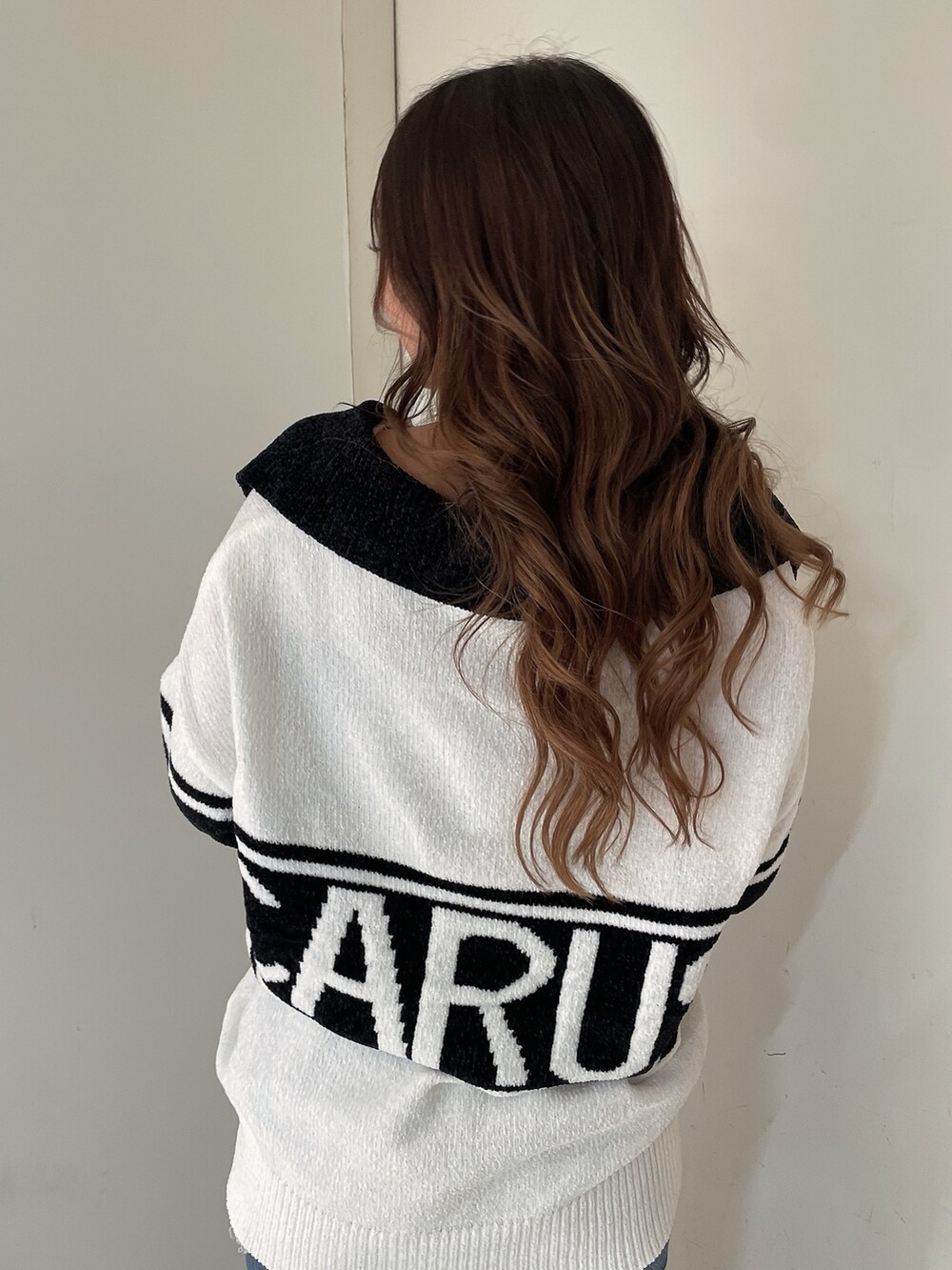 ホワイト系のニット/セーター、ブルー系のデニムパンツ、ホワイト系のパンプスを着用したレディースの秋コーディネートの6枚目の写真