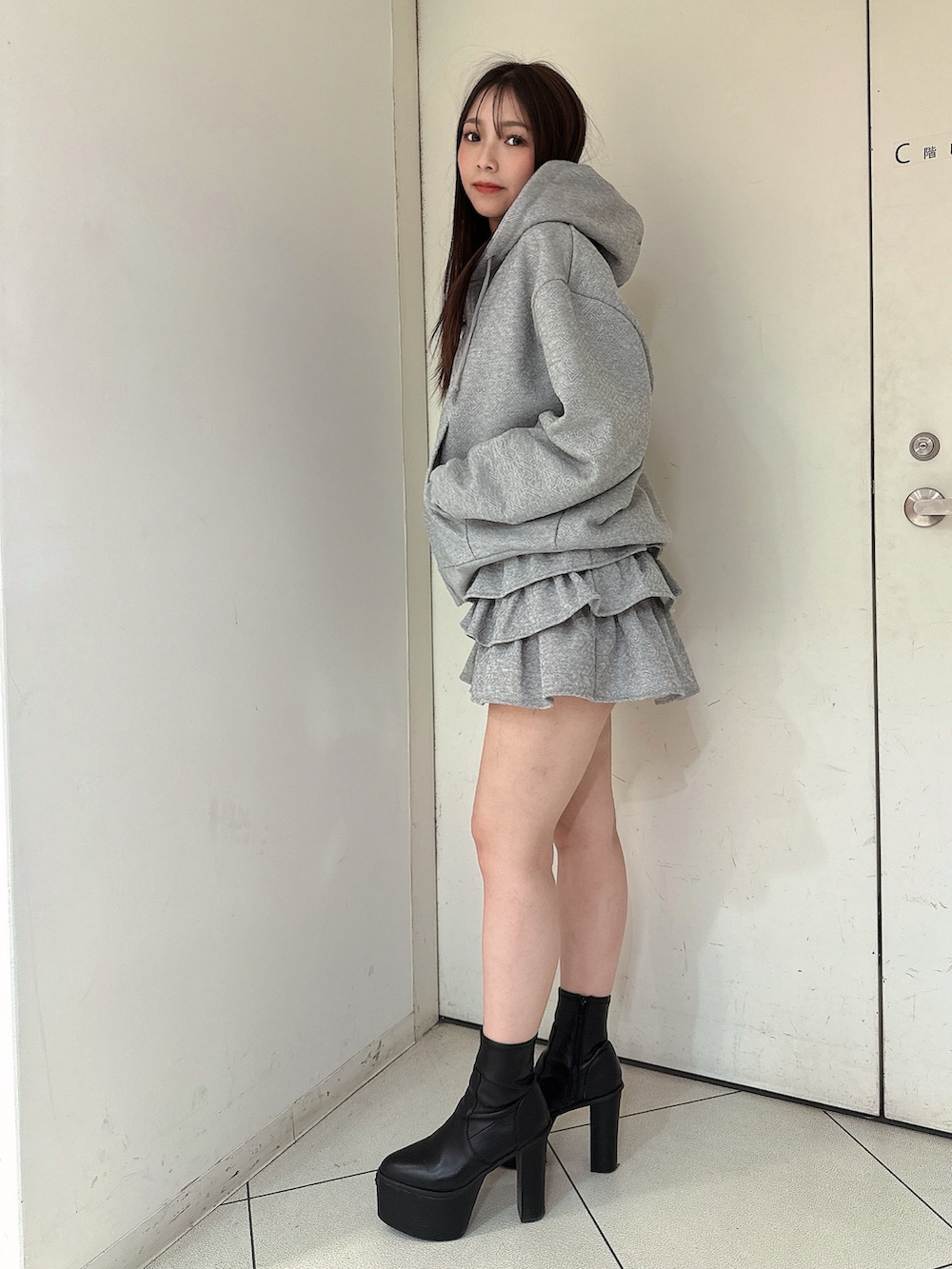 グレー系のスカート、グレー系のパーカー、ブラック系のブーツを着用したレディースの冬コーディネートの2枚目の写真