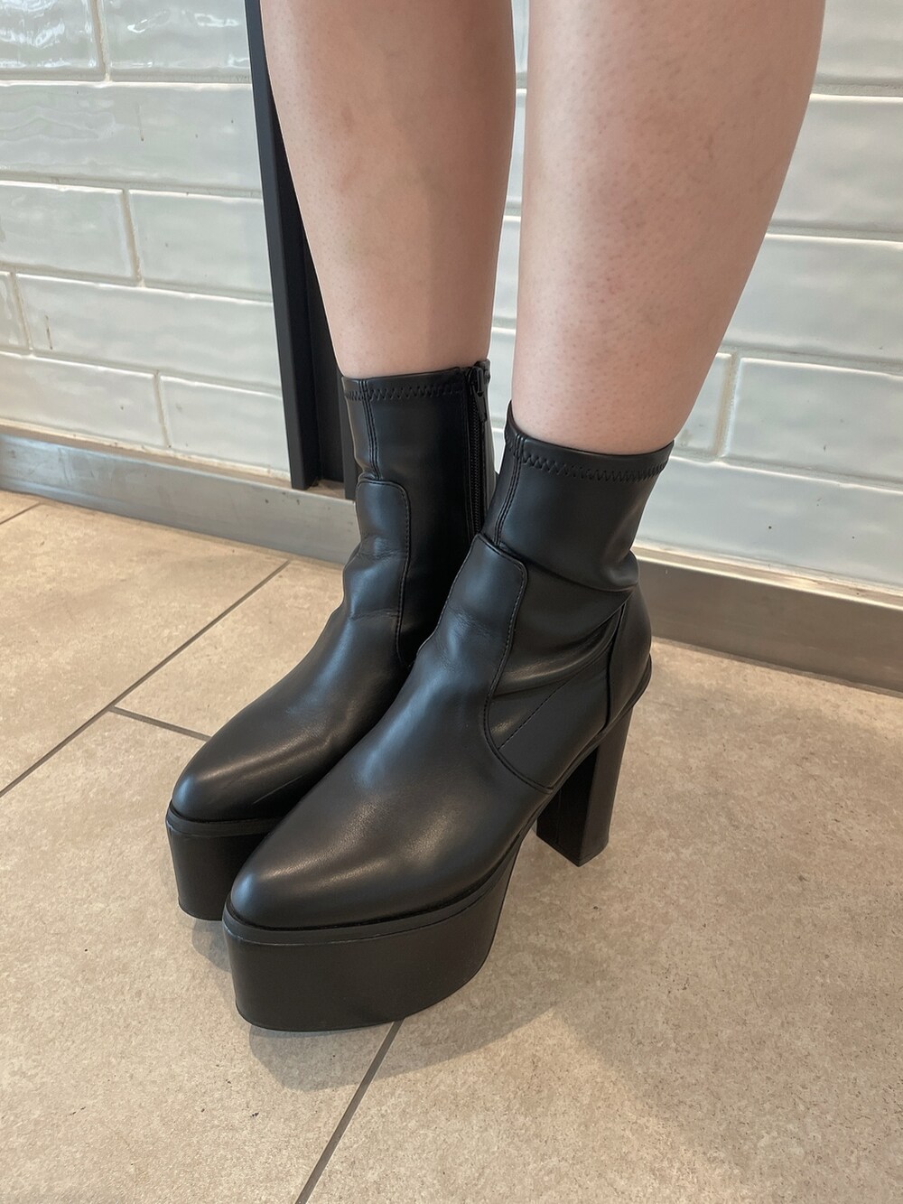 ブラック系のブーツ、ブラック系のデニムパンツ、ホワイト系のスウェットを着用したレディースの秋コーディネートの9枚目の写真