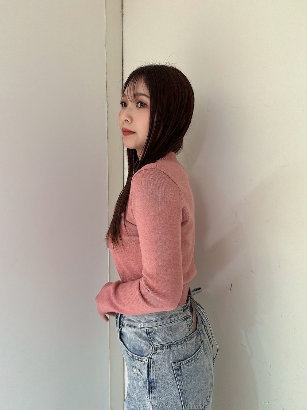 ブルー系のデニムパンツ、ピンク系のニット/セーター、ブラック系のブーツを着用したレディースの冬コーディネートの5枚目の写真