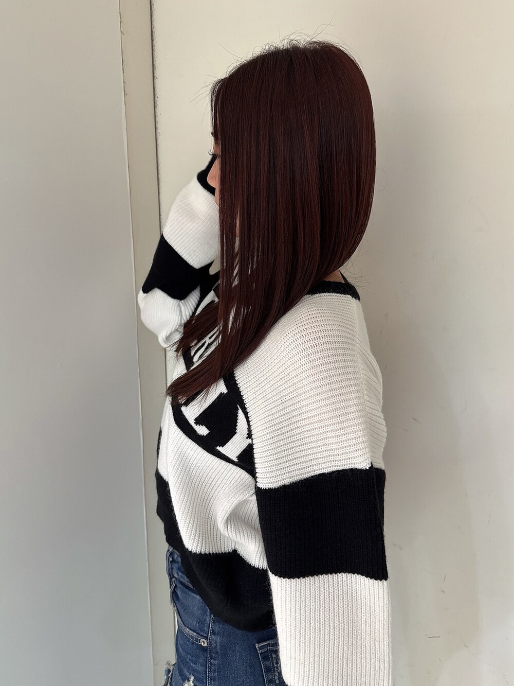 ブルー系のデニムパンツ、ブラック系のブーツ、ブラック系のニット/セーターを着用したレディースの秋コーディネートの5枚目の写真