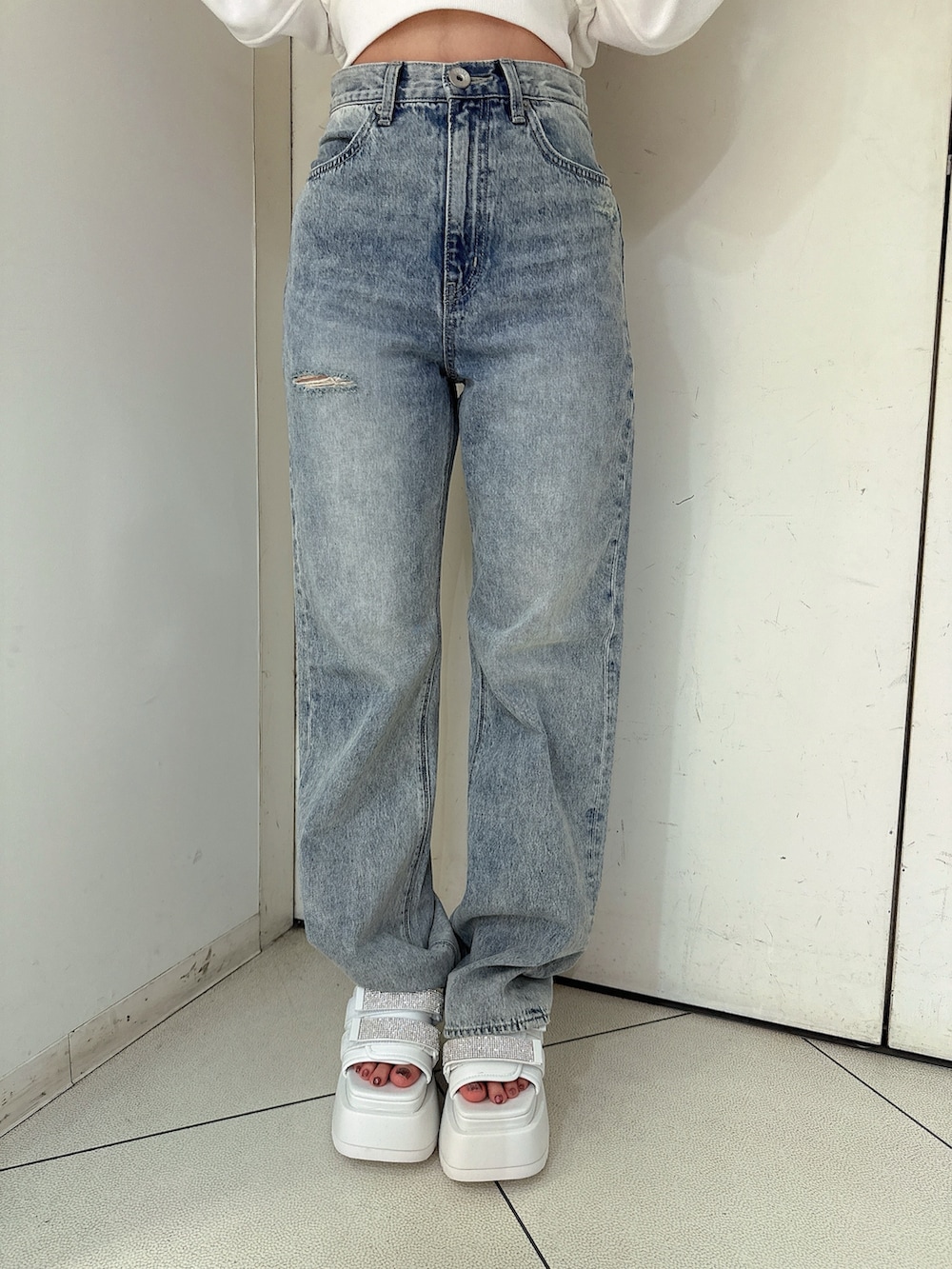 ホワイト系のスウェット、ブルー系のデニムパンツ、ホワイト系のサンダルを着用したレディースの冬コーディネートの9枚目の写真