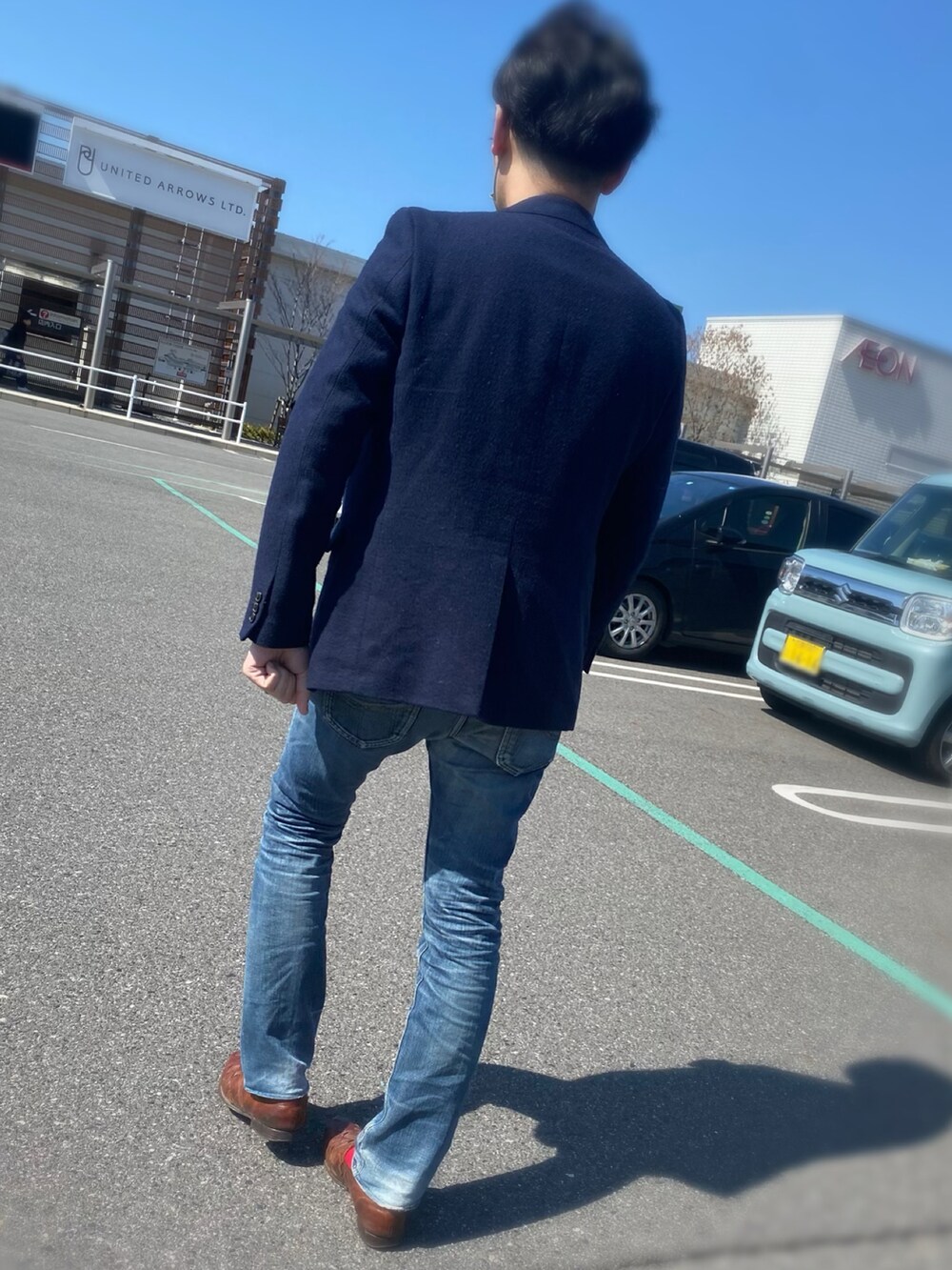 ブルー系のデニムパンツ、グレー系のTシャツ/カットソー、ブラウン系のスリッポンを着用したメンズの春コーディネートの2枚目の写真