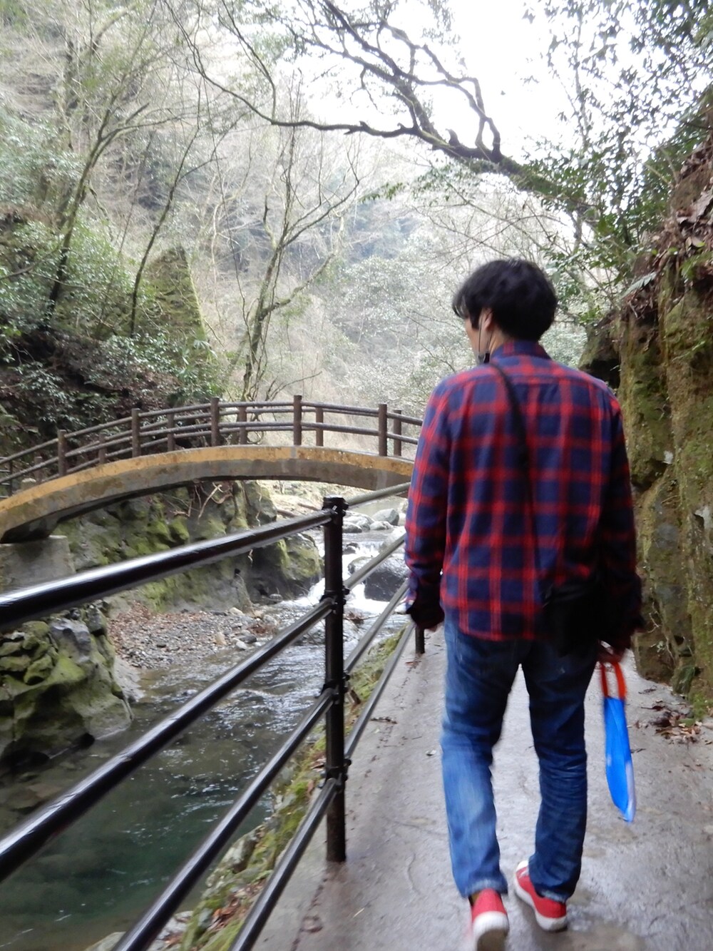 ブルー系のデニムパンツ、レッド系のトップス、レッド系のスニーカーを着用したメンズの冬コーディネートの2枚目の写真