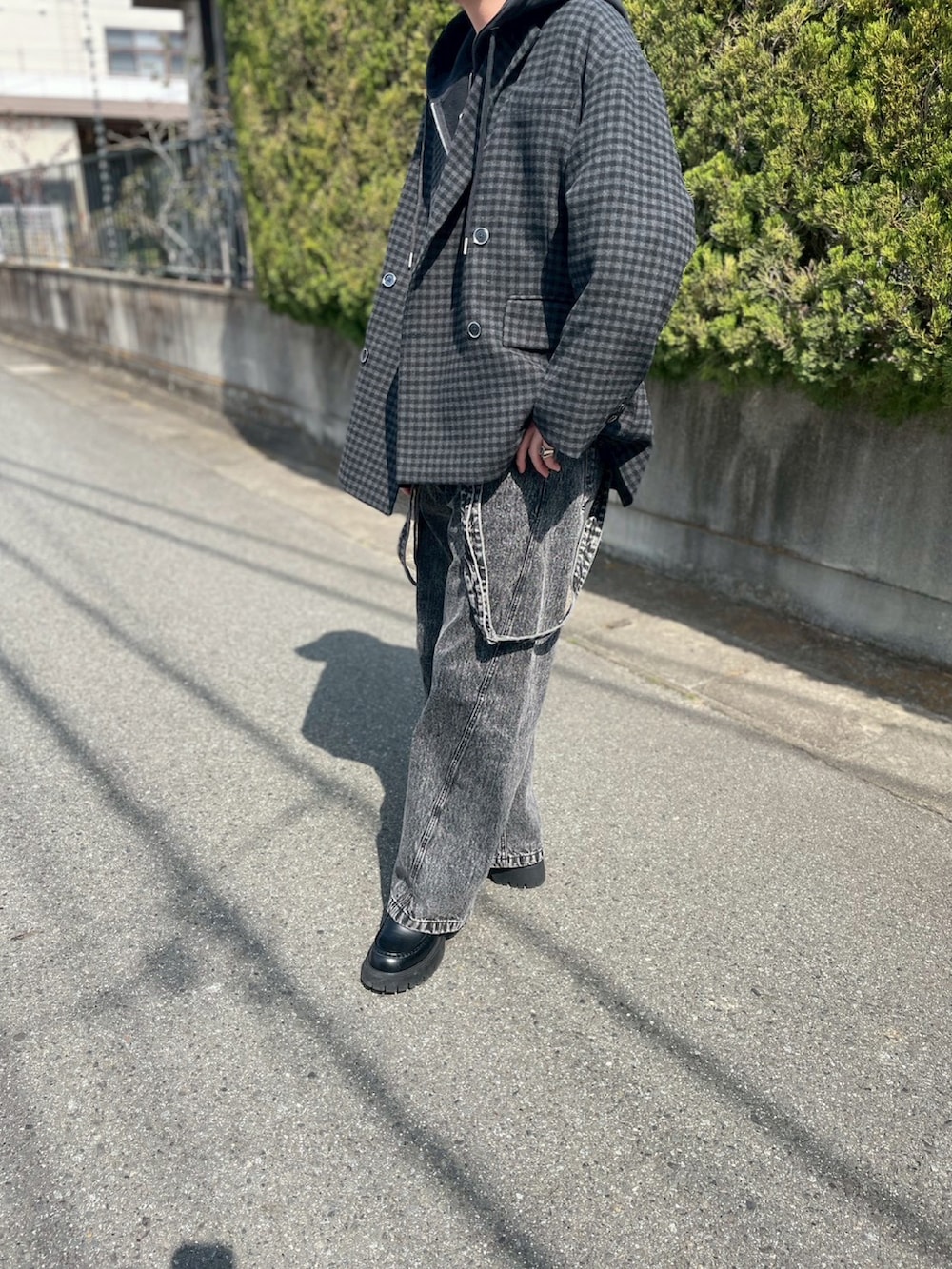 ブラック系のパーカー、ブラック系のテーラードジャケット、ブラック系のデニムパンツを着用したメンズの春コーディネートの2枚目の写真