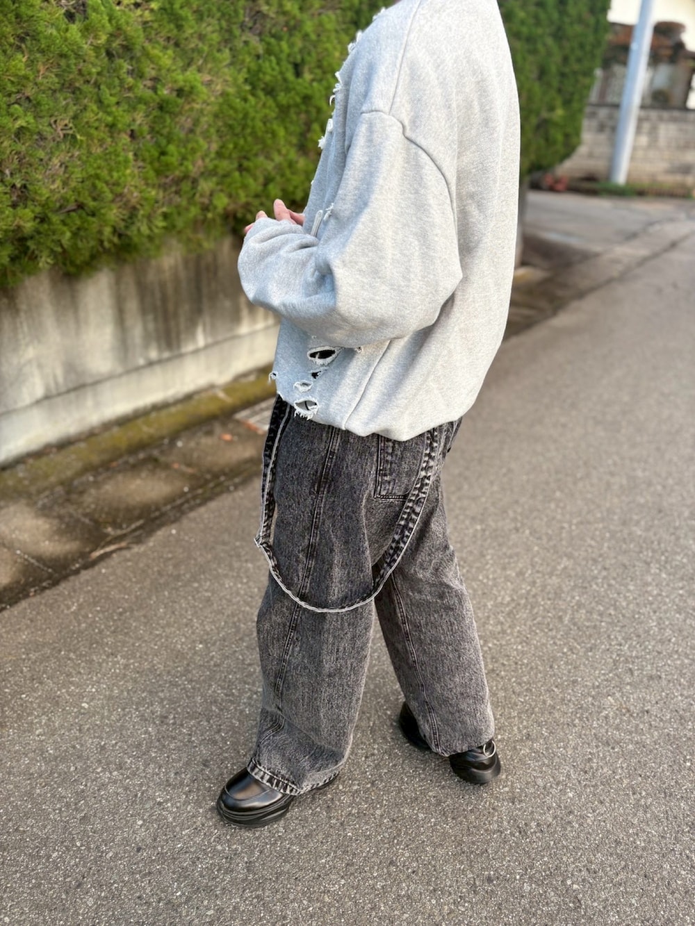 グレー系のスウェット、ブラック系のデニムパンツ、ブラック系のスニーカーを着用したメンズの秋コーディネートの2枚目の写真