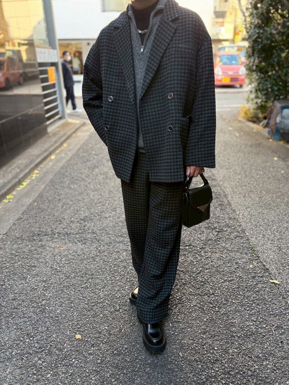 グレー系のニット/セーター、ブラック系のテーラードジャケット、ブラック系のスラックスを着用したメンズの冬コーディネートの2枚目の写真