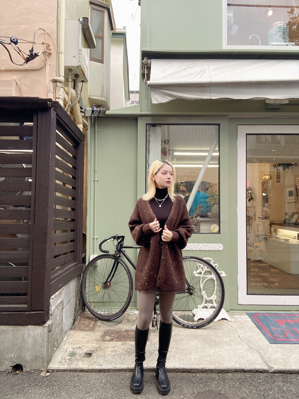 ブラック系のトップス、ブラウン系のカーディガン/ボレロ、シルバー系のネックレスを着用したレディースの冬コーディネートの3枚目の写真