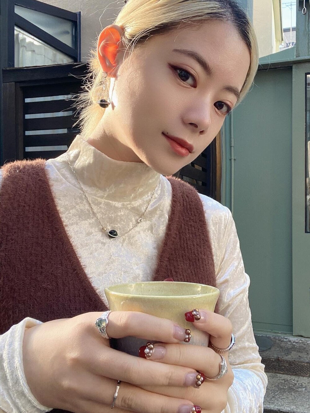 ブラウン系のベスト、ホワイト系のトップス、ブラック系のパンツを着用したレディースの冬コーディネートの4枚目の写真