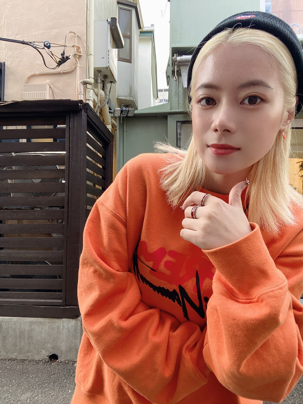 オレンジ系のトップス、ブラック系のデニムパンツ、ブラック系のブーツを着用したレディースの冬コーディネートの3枚目の写真