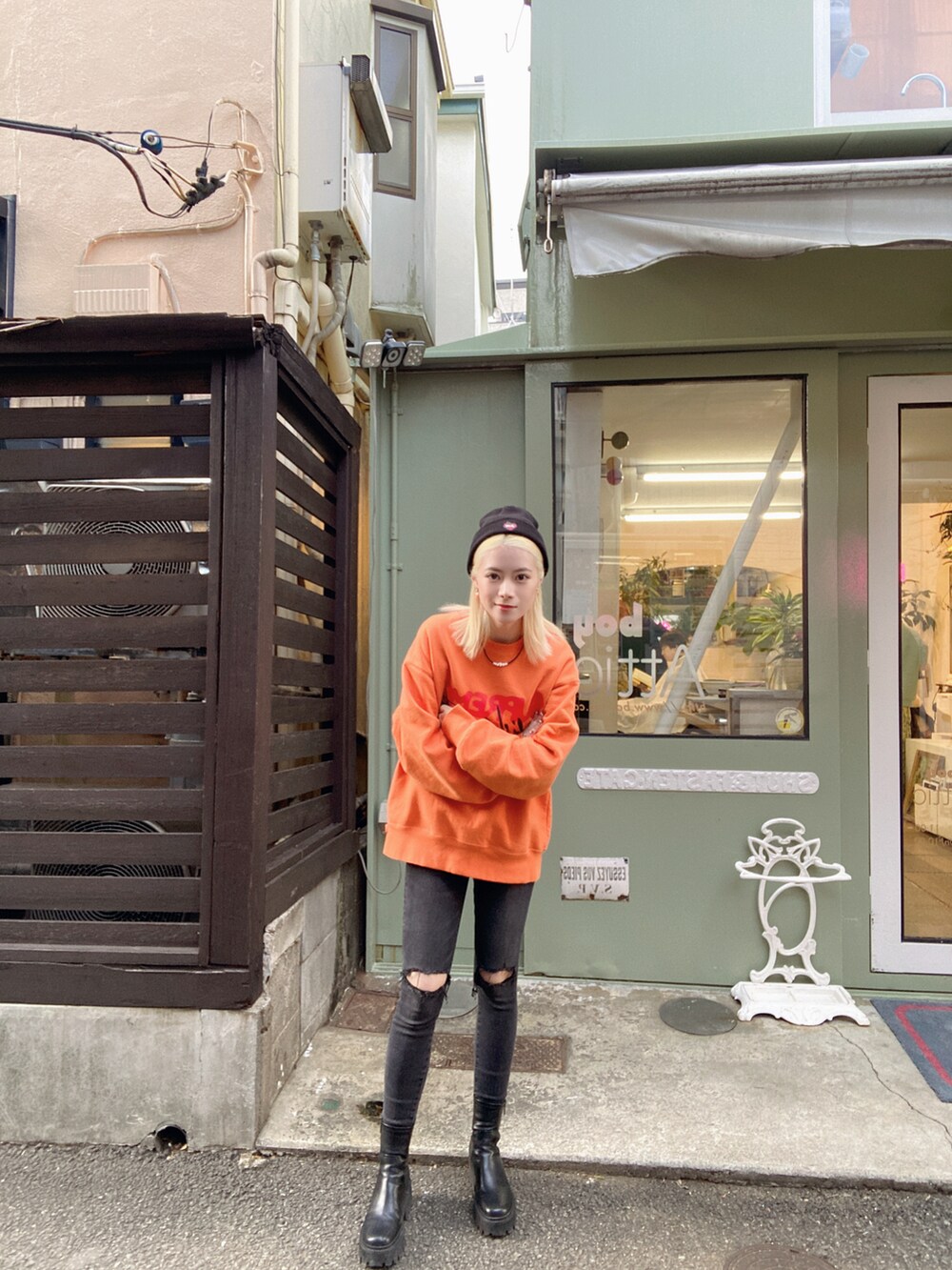 オレンジ系のトップス、ブラック系のデニムパンツ、ブラック系のブーツを着用したレディースの冬コーディネートの2枚目の写真