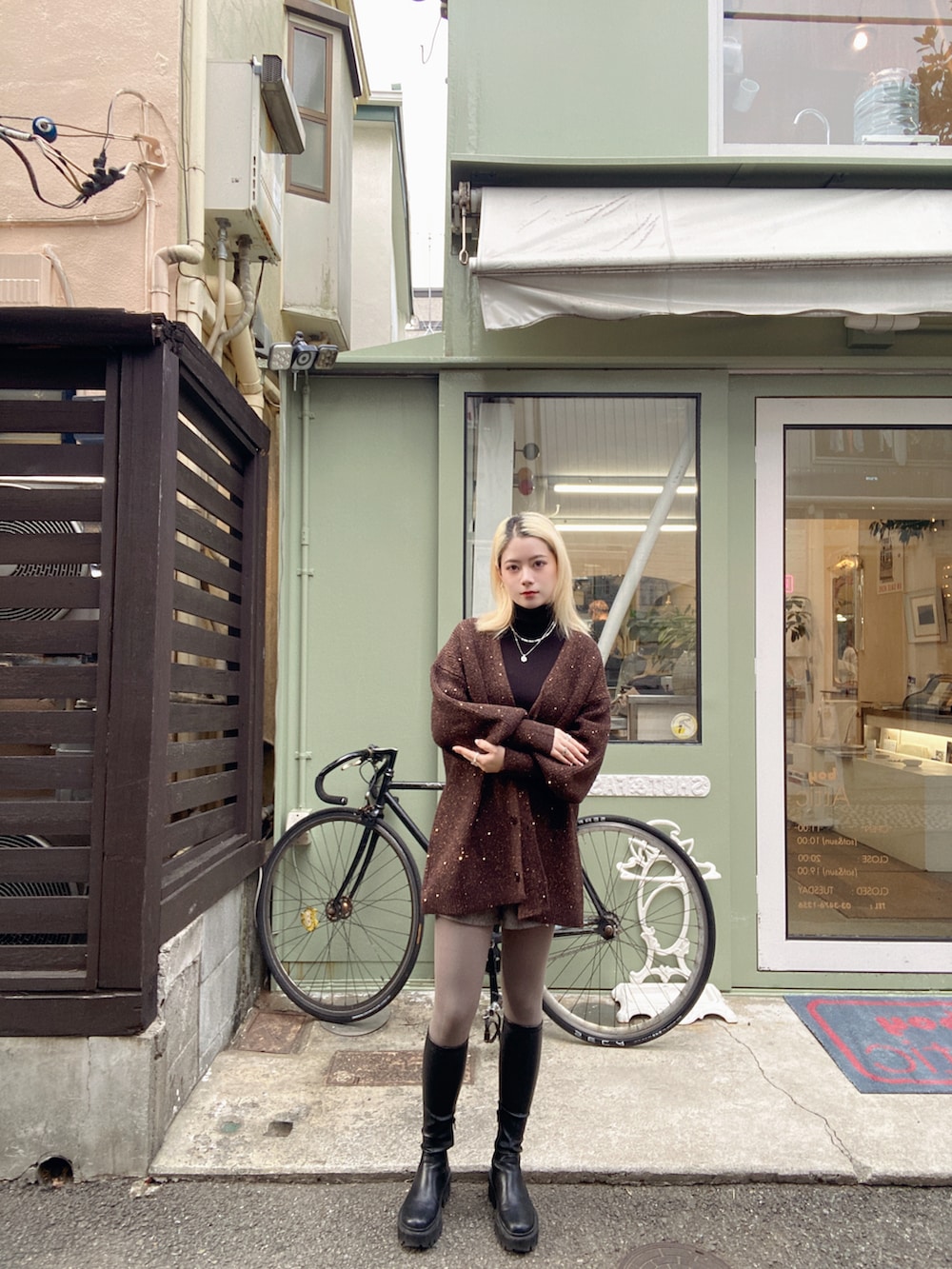 ブラック系のトップス、ブラウン系のカーディガン/ボレロ、シルバー系のネックレスを着用したレディースの冬コーディネートの2枚目の写真