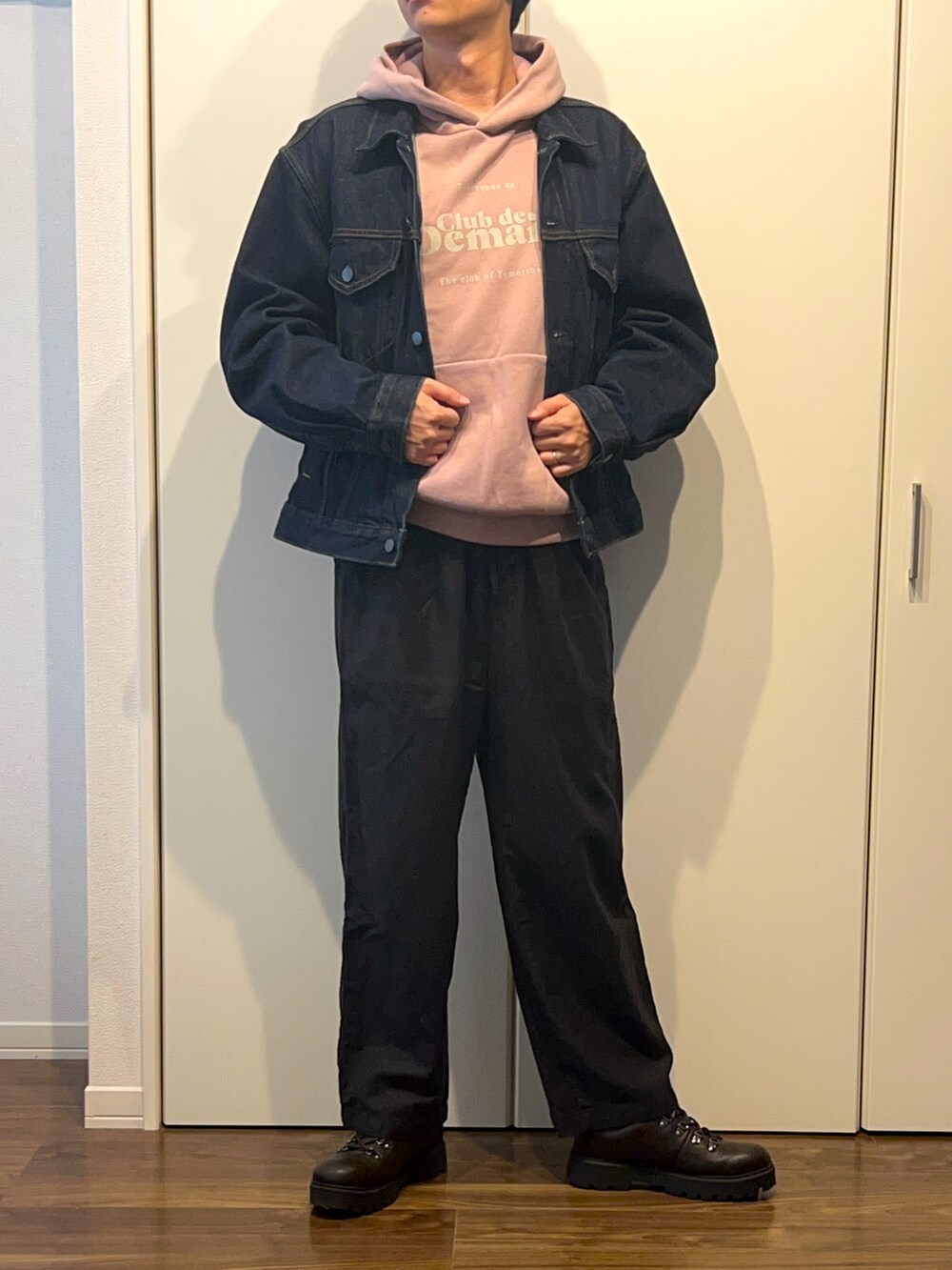 ピンク系のパーカー、ブルー系のデニムジャケット、ブラック系のパンツを着用したメンズの秋コーディネートの3枚目の写真