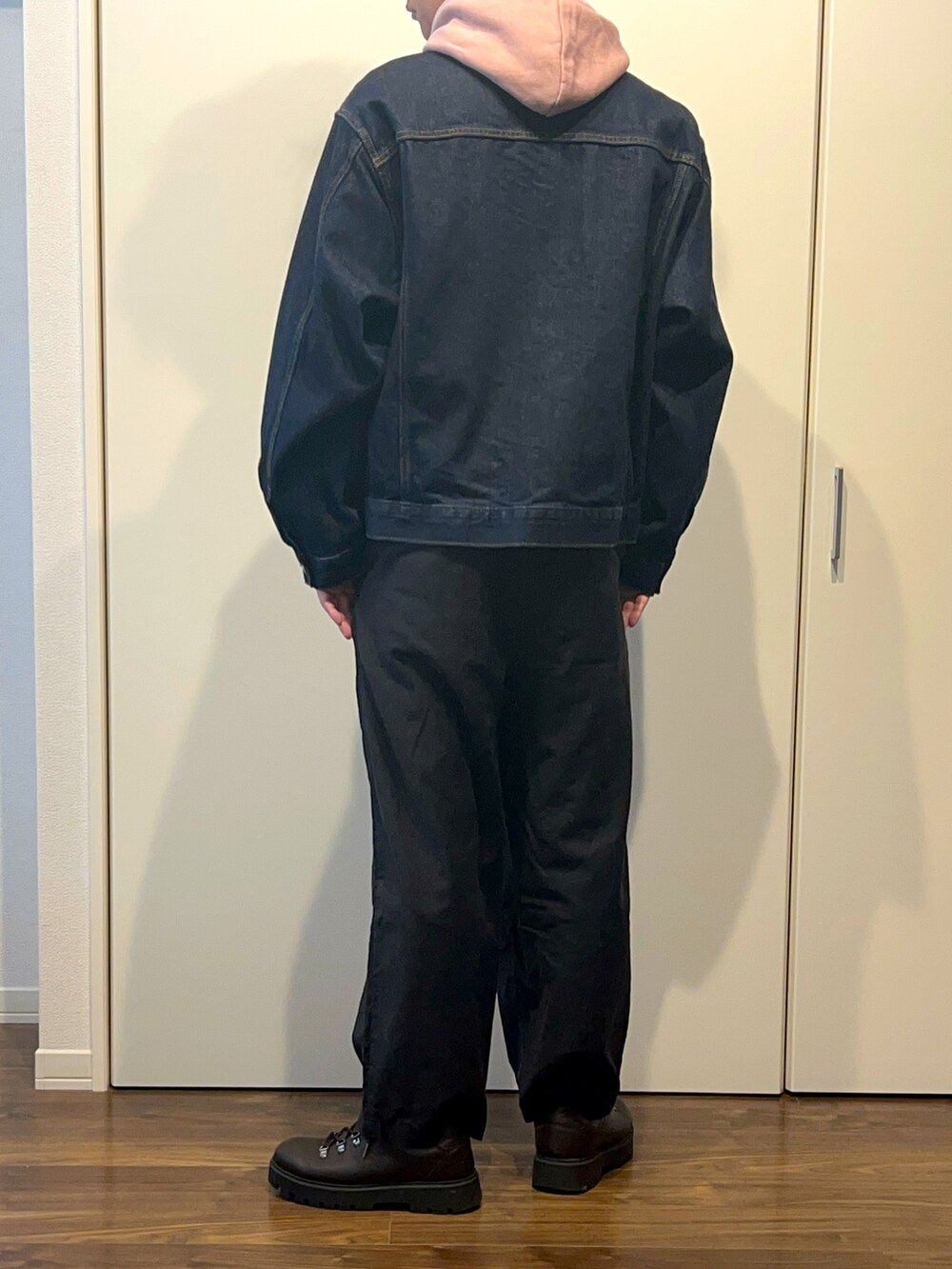 ピンク系のパーカー、ブルー系のデニムジャケット、ブラック系のパンツを着用したメンズの秋コーディネートの2枚目の写真