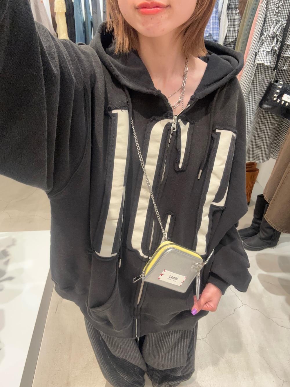 ブラック系のパーカー、グレー系のデニムパンツ、シルバー系の財布を着用したレディースの春コーディネートの3枚目の写真