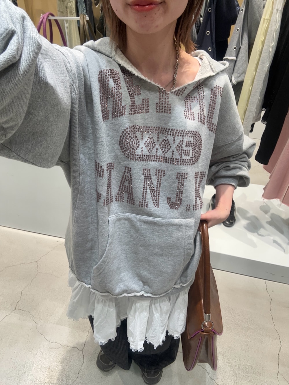 グレー系のパーカー、ホワイト系のチュニック、グレー系のデニムパンツを着用したレディースの春コーディネートの2枚目の写真