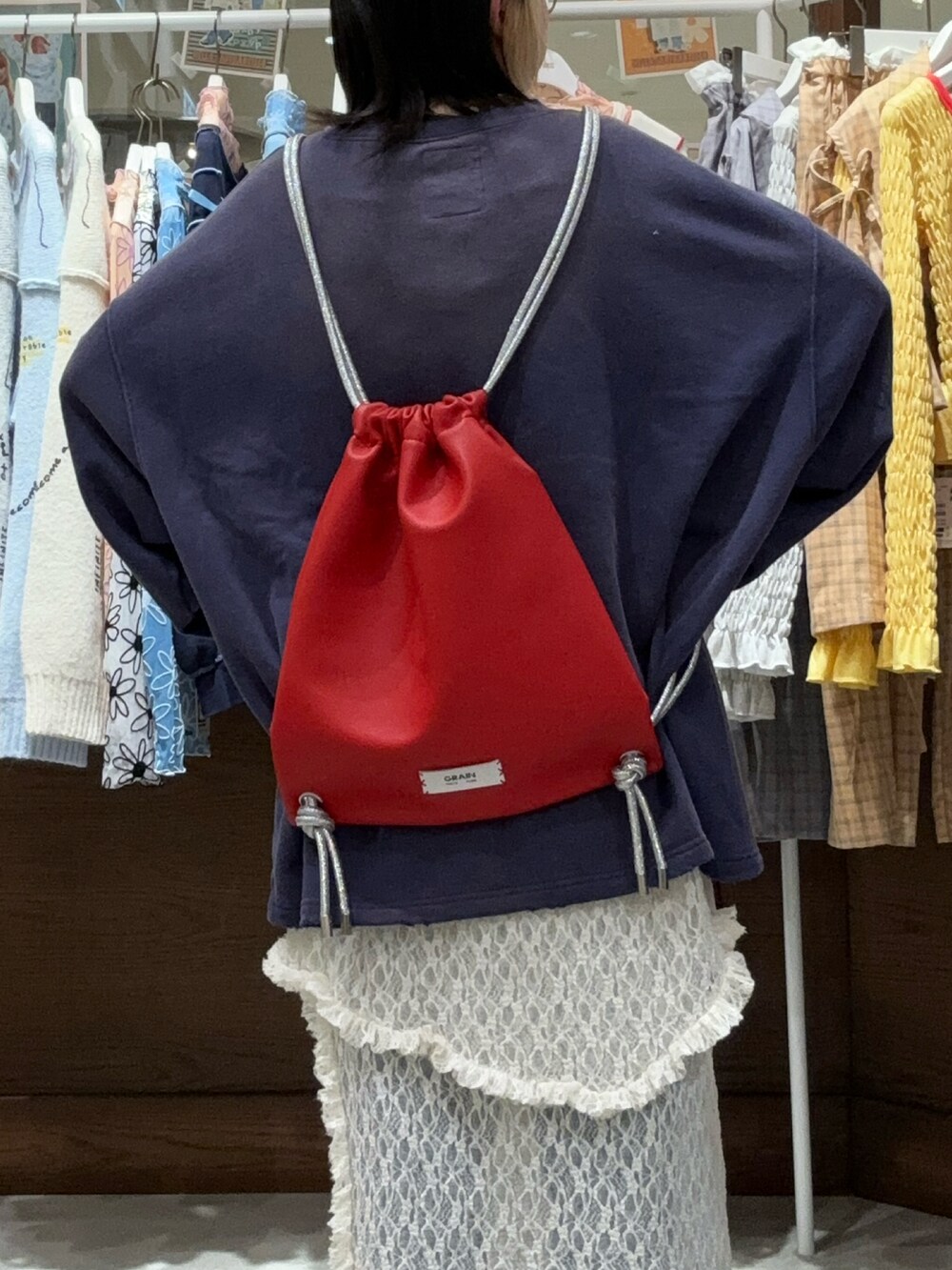 レッド系のバックパック/リュック、ブルー系のスウェット、ホワイト系のスカートを着用したレディースの秋コーディネートの2枚目の写真