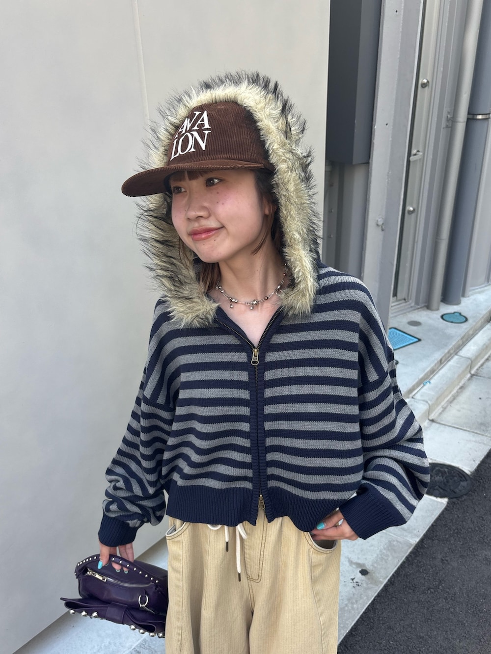ブルー系のパーカー、イエロー系のデニムパンツ、パープル系のショルダーバッグを着用したレディースの秋コーディネートの3枚目の写真