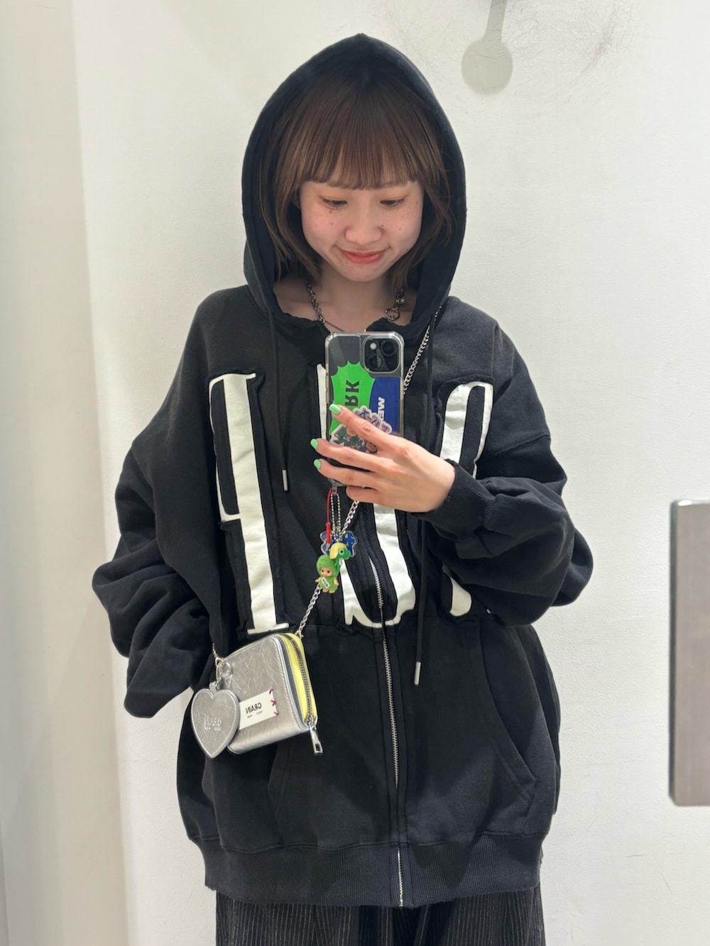 ブラック系のパーカー、グレー系のデニムパンツ、シルバー系の財布を着用したレディースの春コーディネートの2枚目の写真