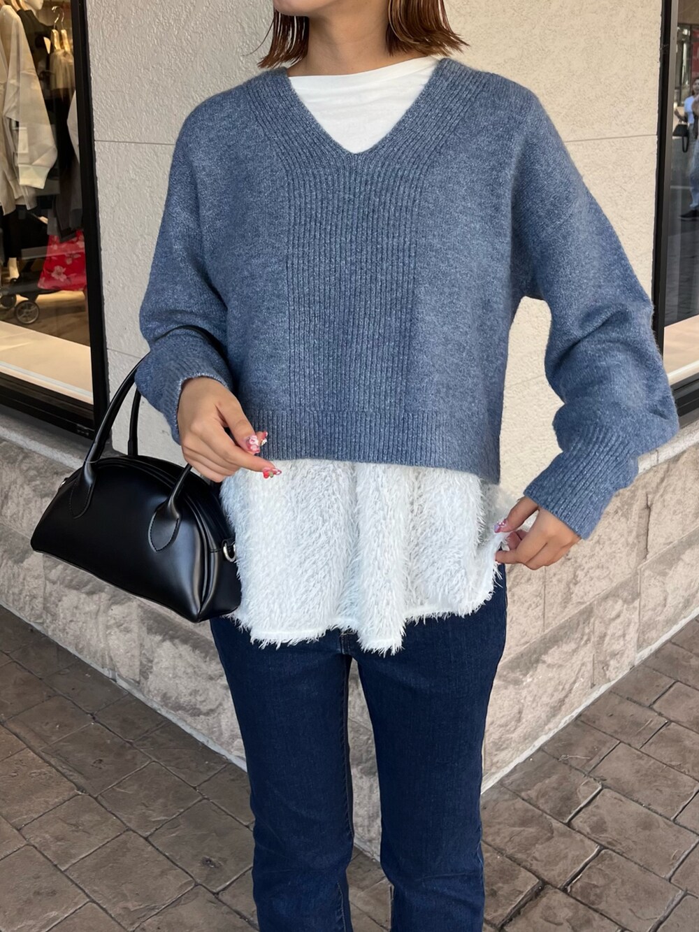 ブルー系のニット/セーター、ブラック系のトートバッグ、ブルー系のデニムパンツを着用したレディースの冬コーディネートの3枚目の写真