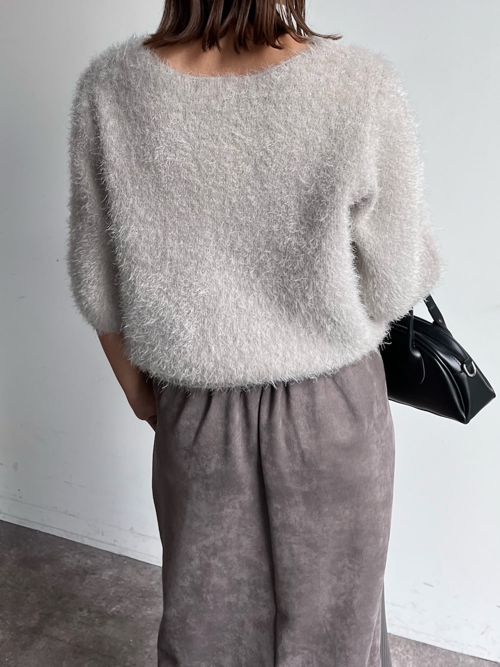 グレー系のニット/セーター、グレー系のスカート、ブラック系のトートバッグを着用したレディースの秋コーディネートの4枚目の写真