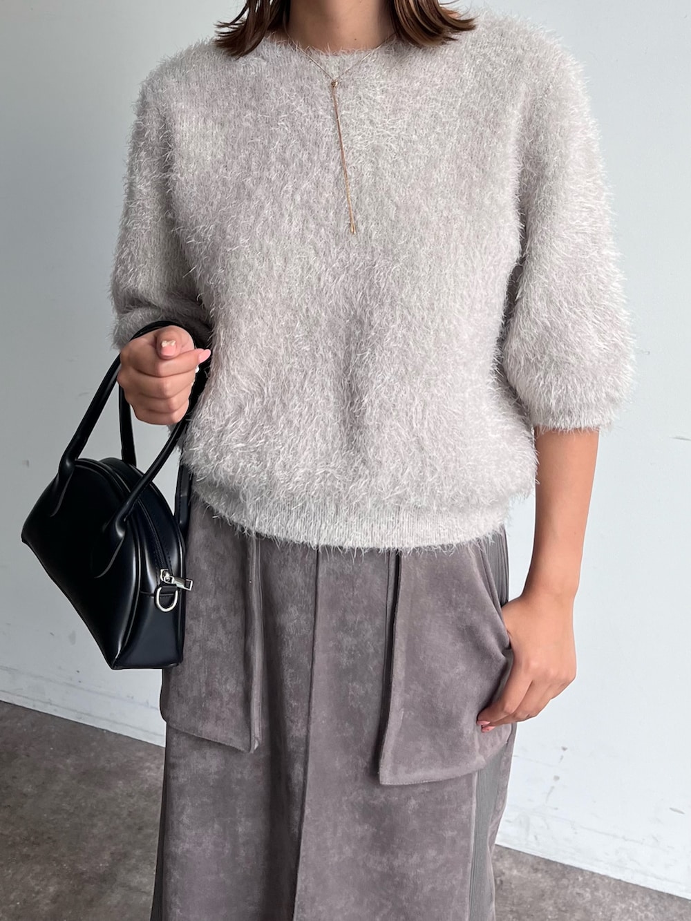 グレー系のニット/セーター、グレー系のスカート、ブラック系のトートバッグを着用したレディースの秋コーディネートの3枚目の写真