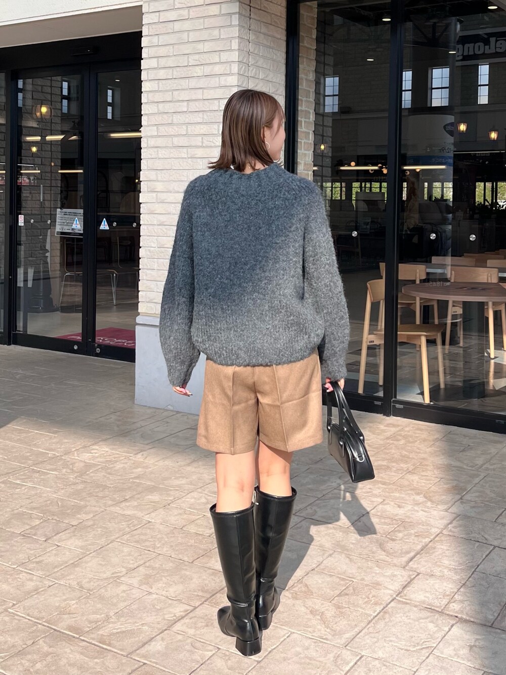 グレー系のニット/セーター、ブラック系のトートバッグ、ブラック系のブーツを着用したレディースの冬コーディネートの2枚目の写真