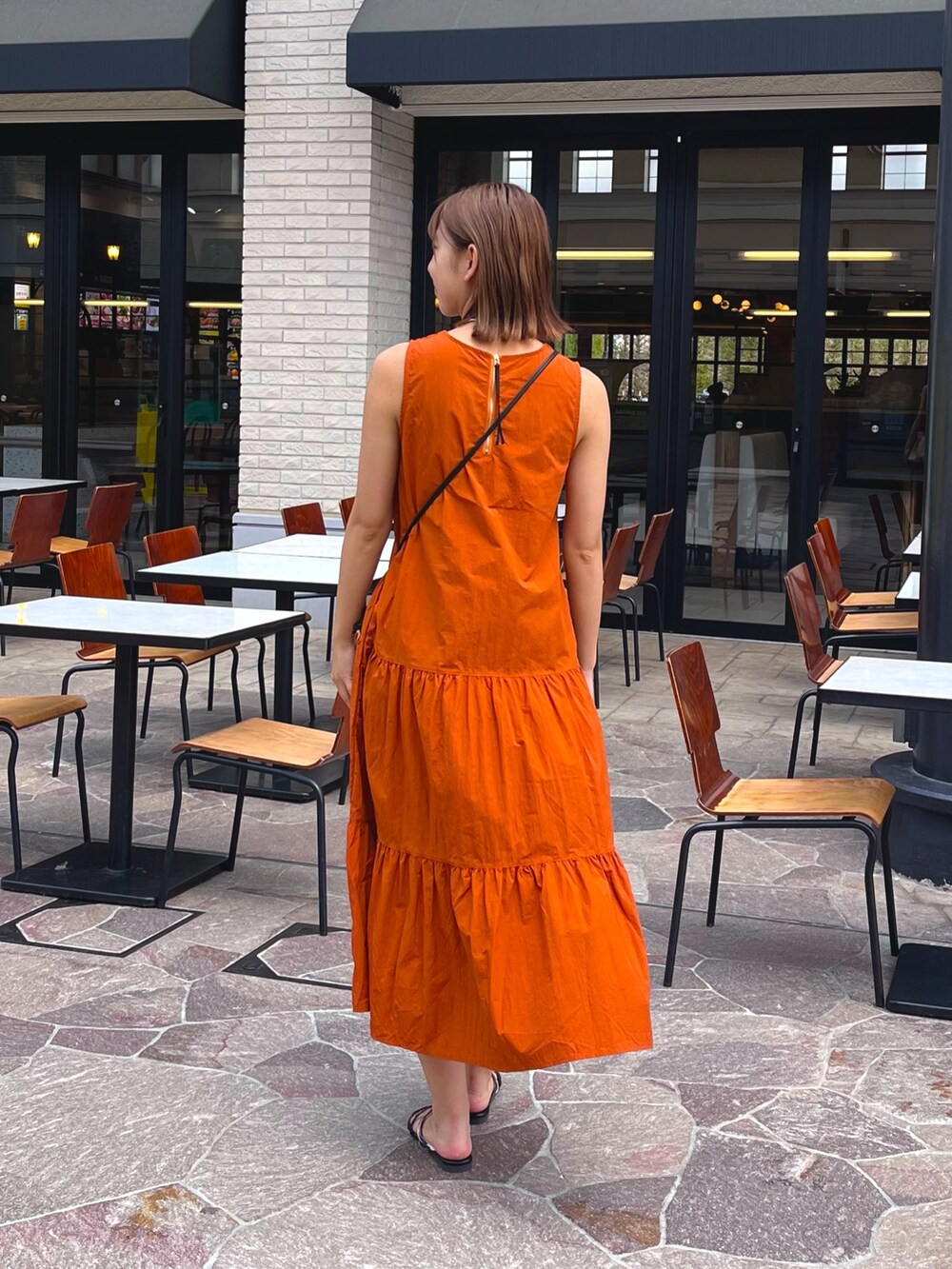 ホワイト系のシャツ/ブラウス、ブラック系のサンダル、オレンジ系のワンピースを着用したレディースの夏コーディネートの4枚目の写真