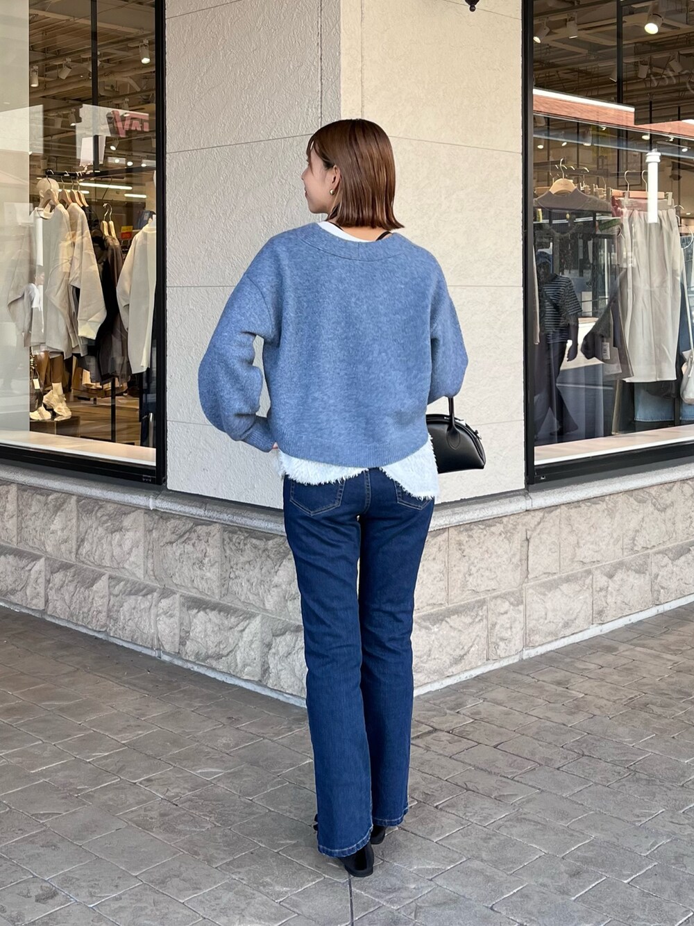 ブルー系のニット/セーター、ブラック系のトートバッグ、ブルー系のデニムパンツを着用したレディースの冬コーディネートの2枚目の写真