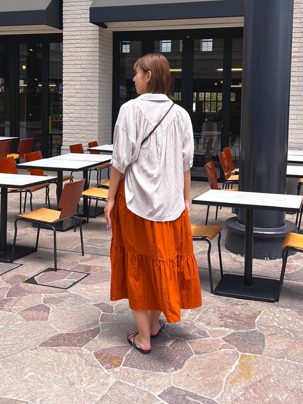 ホワイト系のシャツ/ブラウス、ブラック系のサンダル、オレンジ系のワンピースを着用したレディースの夏コーディネートの2枚目の写真