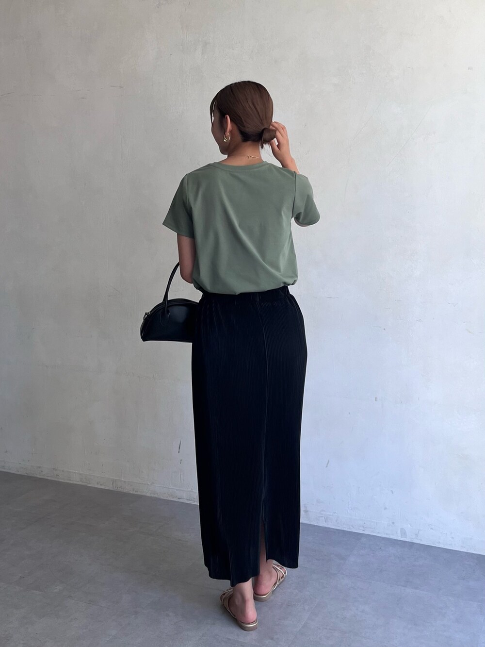 グリーン系のTシャツ/カットソー、ブラック系のスカート、ゴールド系のサンダルを着用したレディースの夏コーディネートの2枚目の写真