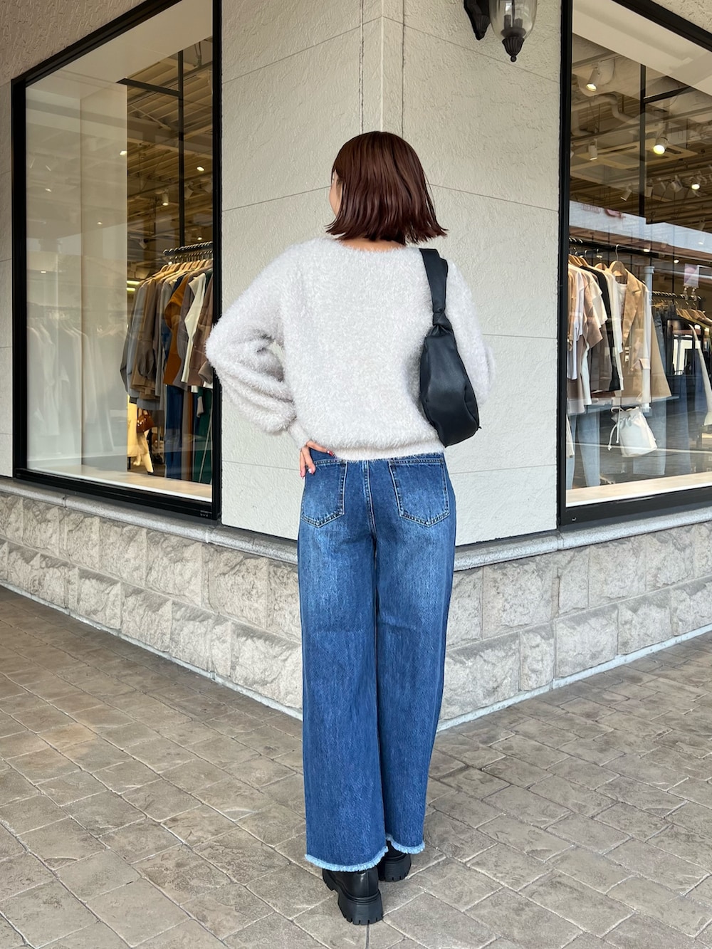 グレー系のニット/セーター、ブルー系のデニムパンツを着用したレディースの秋コーディネートの2枚目の写真