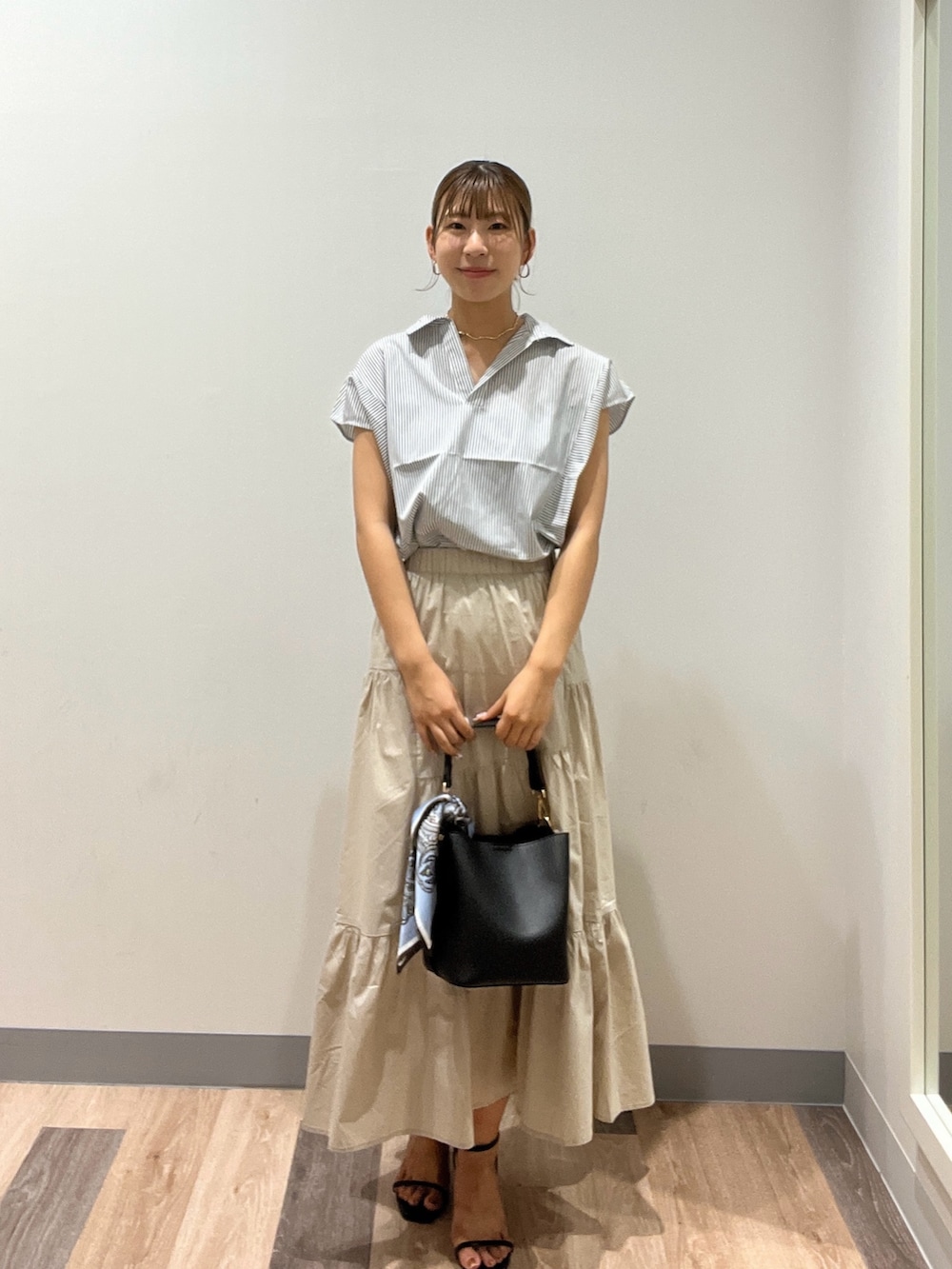 ホワイト系のシャツ/ブラウス、ブラック系のショルダーバッグ、ベージュ系のスカートを着用したレディースの夏コーディネートの2枚目の写真