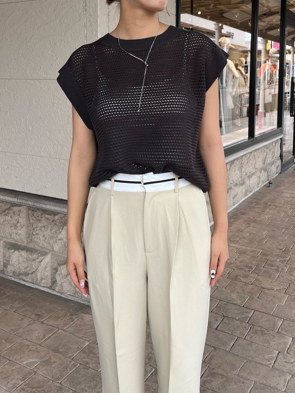 グレー系のニット/セーター、ベージュ系のパンツ、ブラック系のシューズを着用したレディースの夏コーディネートの2枚目の写真