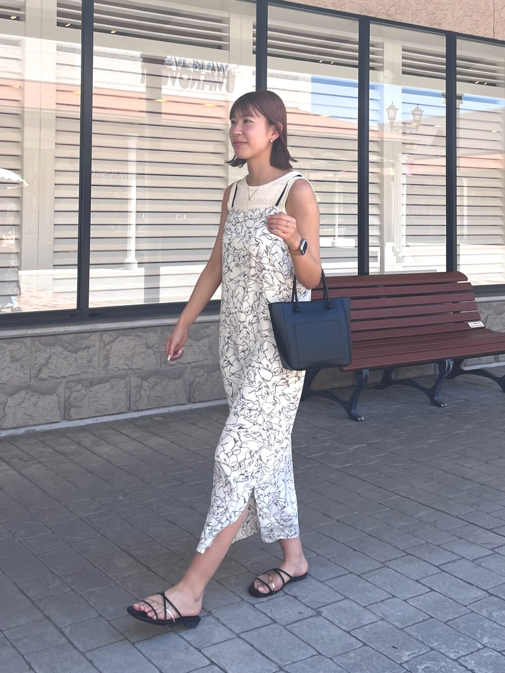 ホワイト系のワンピース、ブラック系のサンダルを着用したレディースの春コーディネートの2枚目の写真