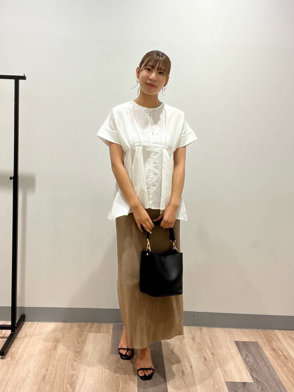 ホワイト系のシャツ/ブラウス、ベージュ系のスカート、ブラック系のショルダーバッグを着用したレディースの夏コーディネートの2枚目の写真