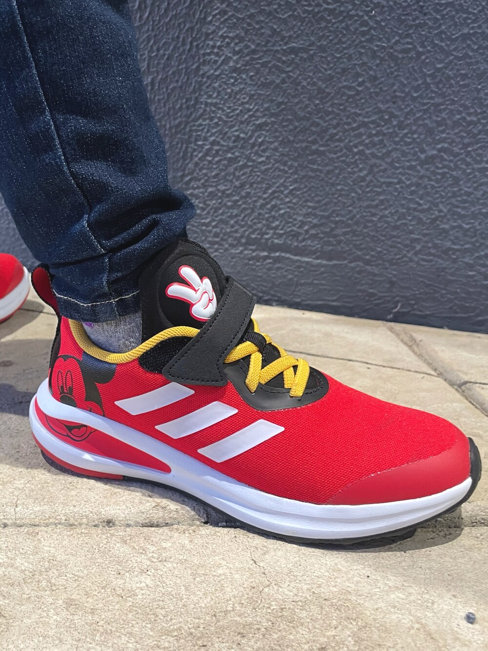 ブラック系のスウェット、ブルー系のデニムパンツ、レッド系のスニーカーを着用したキッズの秋コーディネートの2枚目の写真