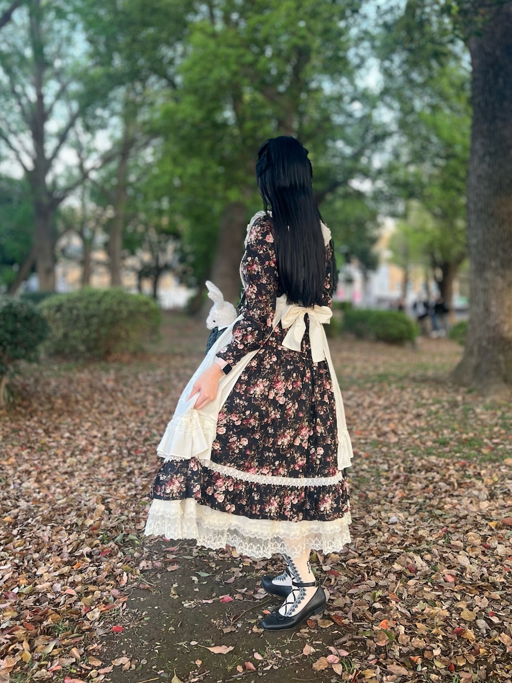 ピンク系のトートバッグ、ブラック系のワンピース、ホワイト系のスカートを着用したレディースの春コーディネートの2枚目の写真