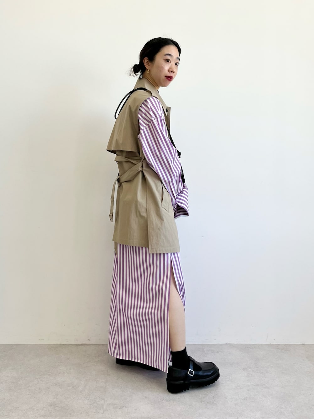 ブラック系のショルダーバッグ、ベージュ系のベスト、パープル系のシャツワンピースを着用したレディースの冬コーディネートの2枚目の写真